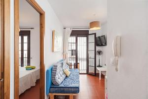 コニル・デ・ラ・フロンテーラにあるEl Patio Apartamento-estudioの青いソファ、ベッド、鏡が備わる客室です。