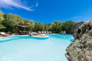 uma piscina com água azul e rochas em Casa Monorosa em Porto Rotondo