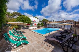 a pool with chairs and umbrellas next to a house at Es Pins Gran in Font de Sa Cala