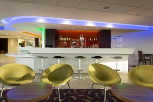 a bar with yellow chairs and tables in a lobby at Holiday Inn Express Dunstable by IHG in Dunstable