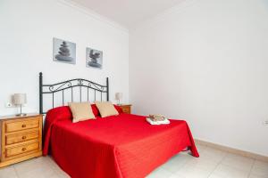 sypialnia z czerwonym łóżkiem i czerwonym kocem w obiekcie Apartamento Doña Alba w mieście Conil de la Frontera