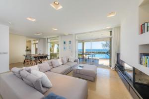 sala de estar con sofá blanco y TV en Port Nou, en Cala Bona