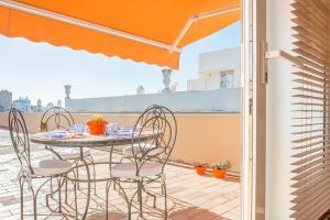 a table and chairs on a balcony with an orange umbrella at Ático en el centro con terraza in Cádiz