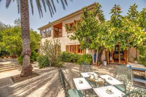 an exterior view of a house with a table and trees at Villa Tramontana in Lloseta