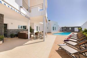 a patio with lounge chairs and a swimming pool at Las Perseidas in Costa Teguise