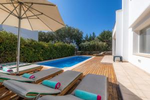 a swimming pool with lounge chairs and an umbrella at Villa Beatriz in Cala d´Or