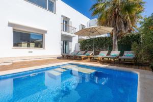 una piscina con sillas y una sombrilla junto a una casa en Villa Beatriz, en Cala d´Or