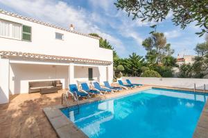 a swimming pool with blue chairs and a house at Villa Mariola in Binibeca