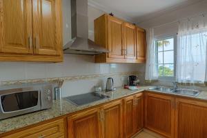 kuchnia z drewnianymi szafkami i mikrofalówką w obiekcie Villa Bini Tuduri w mieście Binibeca