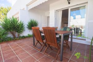 een patio met een houten tafel en stoelen bij La Casa de la Dehesa- Sólo Familias in Conil de la Frontera