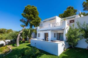 uma grande casa branca com um jardim verde em Beach Apartment 11 em Cala d´Or