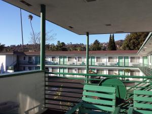 2 sillas verdes sentadas en el balcón de un edificio en Travelers Beach Inn, en Ventura