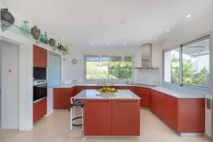 a kitchen with red cabinets and a white counter top at Villa Xipell 9 in Cala Santandria