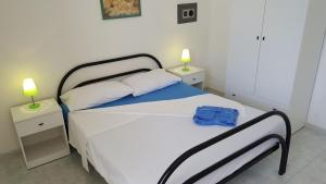 a bedroom with a white bed with two night stands at Trilocale con doppio giardino 9 in Torre dell'Orso