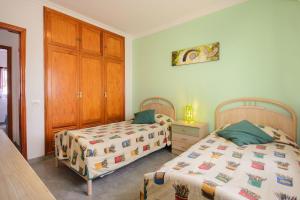 a bedroom with two beds and a wooden cabinet at Apartamento Los Morales in Puerto del Carmen