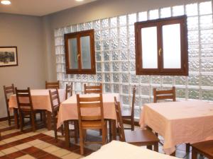 a dining room with tables and chairs and windows at Hostal Patrón in Castañares de Rioja
