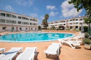 une piscine avec des chaises longues et un hôtel dans l'établissement Lurdes, à Ciutadella