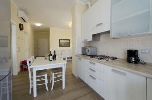 uma cozinha com armários brancos e uma mesa branca com cadeiras em Elegante appartamento al centro storico em Torri del Benaco