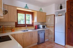a kitchen with wooden cabinets and a white refrigerator at Can Ramon 1 in Sant Josep de Sa Talaia