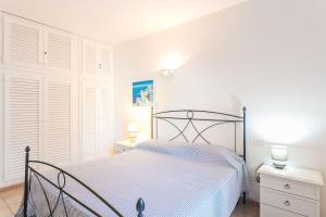 una camera bianca con un letto e due comodini di Residenza Fiorella a San Pantaleo