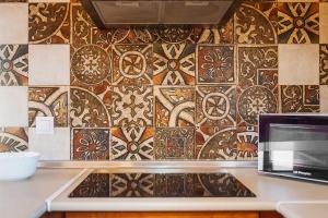 a kitchen with a tile wall with a laptop on a counter at Las tres hermanas in Conil de la Frontera