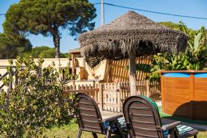 two chairs and a table with a straw umbrella at Las tres hermanas in Conil de la Frontera