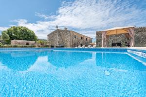 a large swimming pool in front of a stone building at S'era de Son Roig in Sant Joan