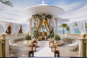 un corridoio nuziale sulla spiaggia con sedie e fiori di Barceló Maya Palace - All Inclusive a Xpu Ha