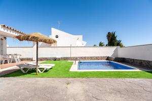 a patio with an umbrella and a swimming pool at Casa Palillero - Sólo Familias in Conil de la Frontera
