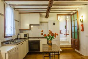 a kitchen with a table with a vase of flowers on it at Can Murenu in Sant Joan de Labritja