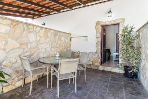eine Terrasse mit einem Tisch, Stühlen und einer Steinmauer in der Unterkunft Magnolia B- Solo Familias in Conil de la Frontera