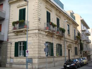 un edificio con balcones y coches aparcados en una calle en La Maison des Livres, en Reggio Calabria