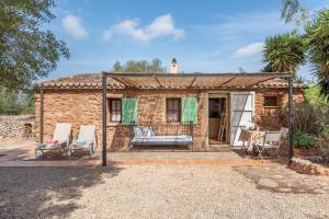 a stone house with two chairs and a porch at Es Rafal Roig - Es Galiner in Sant Llorenç des Cardassar