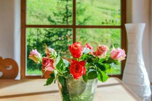 eine Vase aus Rosen auf einem Tisch mit einem Fenster in der Unterkunft Chalet am Brand in Tegernsee