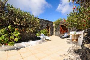 un patio con 2 sillas, una mesa y algunos arbustos en La Bodega - House on volcano with a piano, en Haría