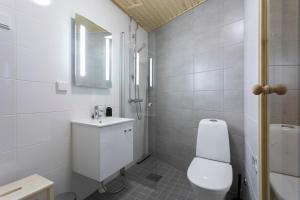 a white bathroom with a toilet and a sink at Vasko luxurious suites, Mustikka in Rovaniemi +11 photos