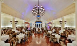 una sala da pranzo con tavoli, sedie e un lampadario di Barceló Maya Palace - All Inclusive a Xpu Ha