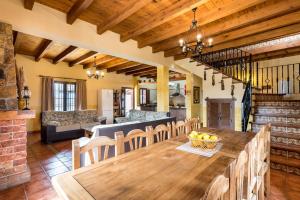 a kitchen and living room with a wooden table and chairs at Casa Rural Loma El Letrao in Almogía