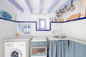 a kitchen with a sink and a washing machine at Casa Rural El Tesillo in Canillas de Aceituno