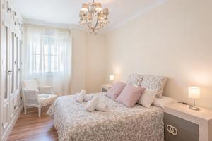 een witte slaapkamer met een bed met roze kussens bij House Sun Beach 2 in Vejer de la Frontera