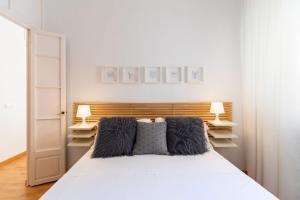 Un dormitorio con una cama blanca con dos almohadas. en La Torre de Menacho, en Cádiz