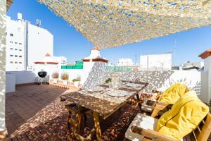 Un patio con una mesa y sillas en un tejado. en La Torre de Menacho, en Cádiz