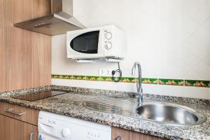 a kitchen with a sink and a microwave at Estudio Lila in Conil de la Frontera +18 photos