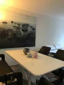 einen weißen Tisch mit Stühlen und ein Gemälde an der Wand in der Unterkunft Rhein Promenade in Basel
