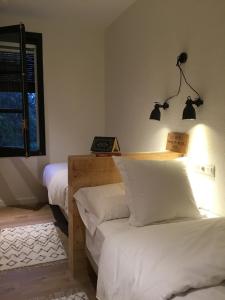 a bedroom with two beds and a lamp on the wall at Hostal Can Maret in Vilademuls