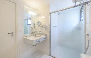 a white bathroom with a sink and a shower at Mercure Sao Paulo Alamedas in Sao Paulo