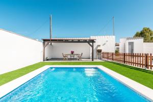 una piscina en el patio trasero de una casa con mesa en Casa Hefestión en Conil de la Frontera