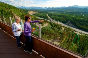 a woman and a man standing on a ledge near a river at Grande Denali Lodge in McKinley Park