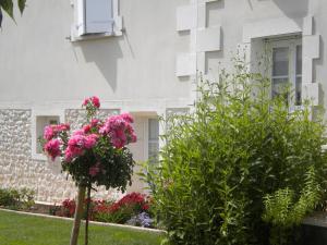 a white building with pink flowers in a yard at Au Paradis des Hôtes in Fouras
