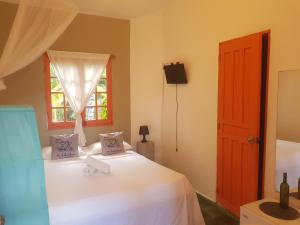 a bedroom with a white bed with a window at Casa Delfin Guest House in Las Terrenas